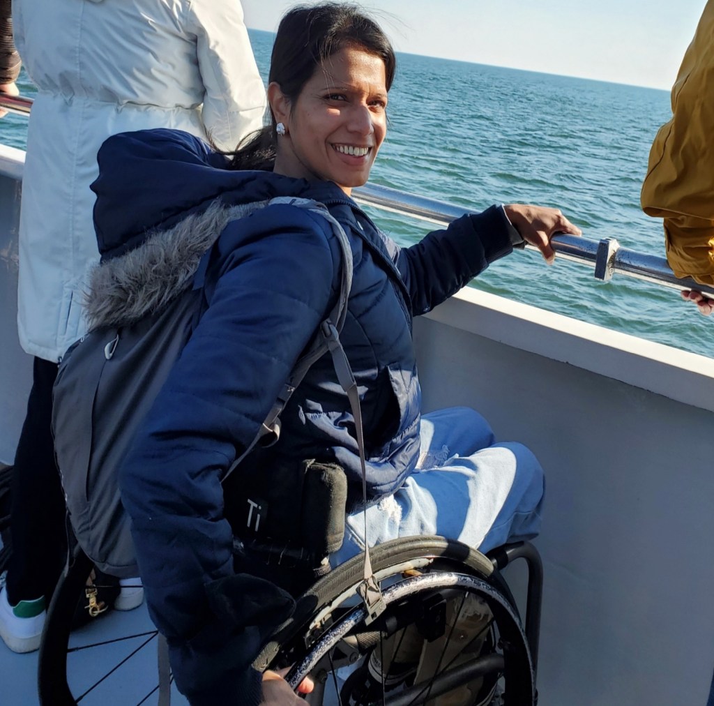 Maggie in her wheelchair holding onto the boat railing.